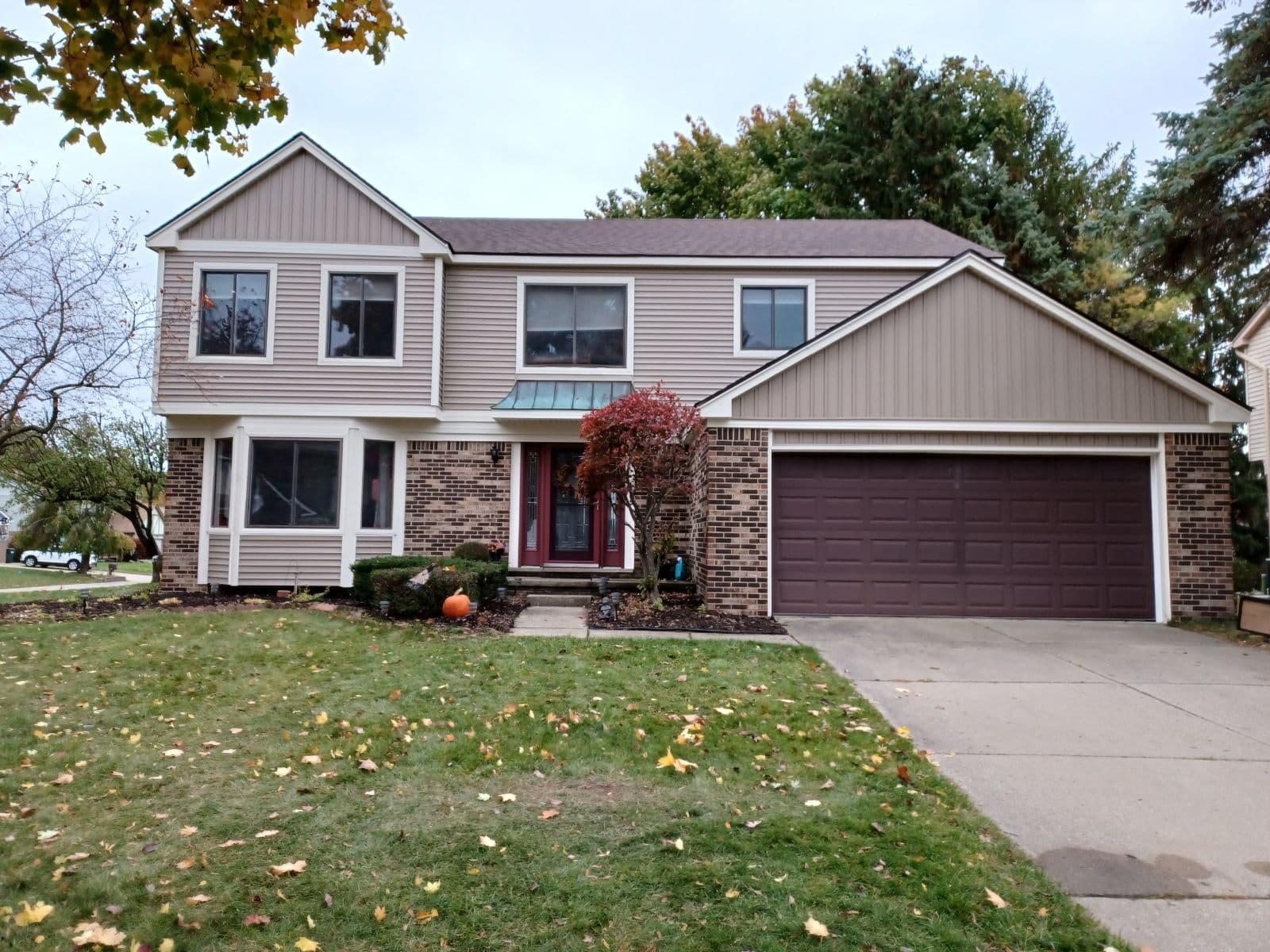 Two-story suburban home with brick and siding, landscaped yard, and double garage.