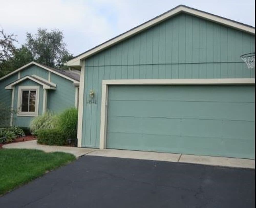 Light blue residential house with garage, driveway, and well-maintained landscaping.